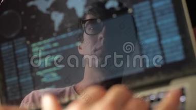 双曝光：戴眼镜的人在笔记本电脑上工作。 程序员写蓝色代码，在监视器中反射