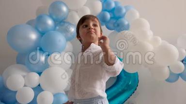 两岁的男孩穿着白色衬衫，穿着蓝色<strong>气球坐</strong>在家里