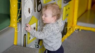 可爱的小男孩在墙上玩忙碌的木板。 教育玩具。 儿童专用餐