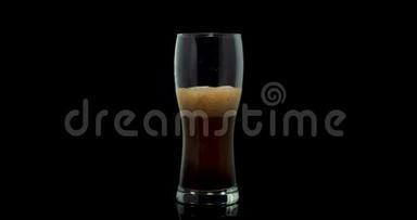 一家私人酿酒厂用焦糖麦芽酿造的黑色工艺啤酒倒入黑色背景的玻璃杯中