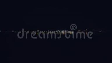 夜晚，水上的建筑物闪闪发光，夜晚的城市在海湾海滨的灯光下
