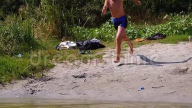 男孩<strong>跑到</strong>海滩岸边的水中，在河中制造飞溅。 慢动作