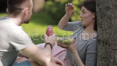 年<strong>轻</strong>的素<strong>食</strong>夫妇坐在公园里吃<strong>沙拉</strong>和喝冰沙