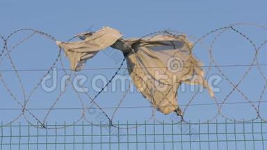 围栏监狱严格制度.. 在一个刮风的日子里，一件<strong>撕破</strong>的衣服逃犯挂在铁丝网上。 非法移民概念