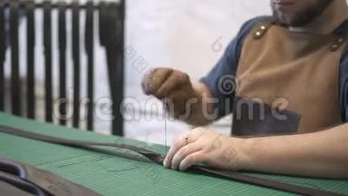 工匠在车间用人造皮革制作的黑色袋子手柄上工作。