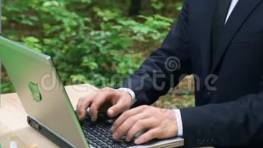 穿着正式服装，坐在森林里的笔记本电脑打字，环保技术