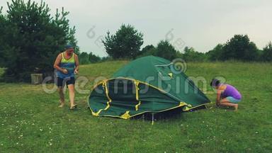 一男一女用木桩拉着帐篷的上帐篷..