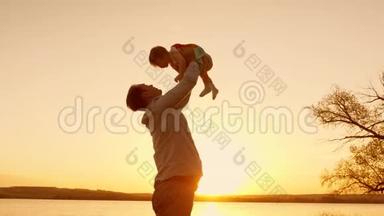 爸爸在日落时和他的女儿玩，用手把他的小女儿高高地举到天空。 慢动作