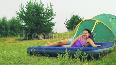 帐篷附近空地上的一个女人躺在充气床垫上。