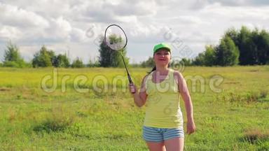 一个在空地上打羽毛球的女人发球和击球。