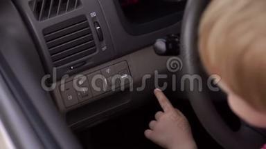 小男孩坐在汽车的车轮后面，他按下按钮<strong>打开后备箱</strong>。