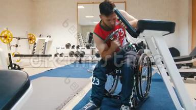 坐轮椅的英俊残疾人在有重量的健身房训练。
