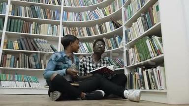 年轻的非洲夫妇在图书馆准<strong>备考</strong>试时，坐在书架附近的地板上。
