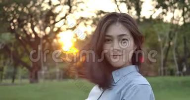 年轻迷人的亚洲女人的肖像在<strong>夕阳</strong>下的<strong>夏日</strong>公园里开心地微笑着进入镜头。