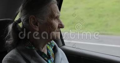 一位皱纹很深的祖母坐在车里，<strong>望</strong>着<strong>窗外</strong>。