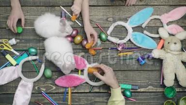 画复活节彩蛋和用胡萝卜喂复活节野兔的手的俯视图。 幸福的家庭正在准备复活节