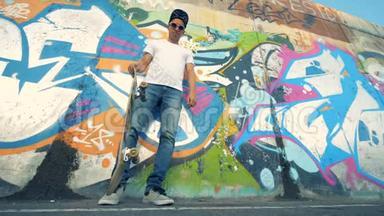 涂鸦墙和一个年轻人用腿举起<strong>滑板</strong>