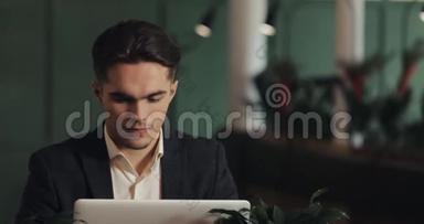 快乐的年轻商人坐在咖啡馆里用笔记本电脑工作。 胜利者看着手提电脑显示出是的姿态，庆祝