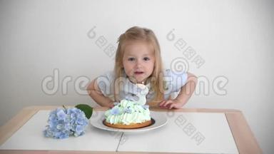 一个3岁的女孩许愿在蓝色蛋糕上吹蜡烛