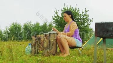 <strong>一个</strong>年轻的女人坐在<strong>一个</strong>木头树桩旁边，从盘子里吃<strong>东西</strong>。