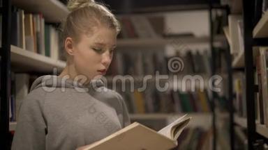 一个年轻的金发女孩在图书馆的书架间看书