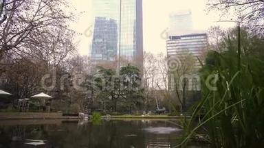 中国上海市中心摩天大楼背景下的池塘公园