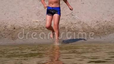 男孩跑到海滩岸边的水中，在河中制造飞溅。 慢动作