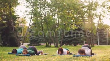 穿运动服装的瘦小女孩在公园的户外课堂上一起做瑜伽，锻炼身体