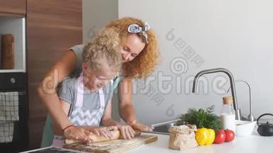 漂亮的年轻妈妈和她可爱的小女儿在家里擀面团。