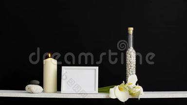 现代客房装饰与相框模型。 用装饰蜡烛、玻璃和岩石搭在黑色墙壁上。 蜡烛燃烧