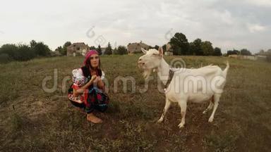 一个穿着乌克兰传统<strong>民俗</strong>服装的年轻女子自己喂苹果，喂白山羊