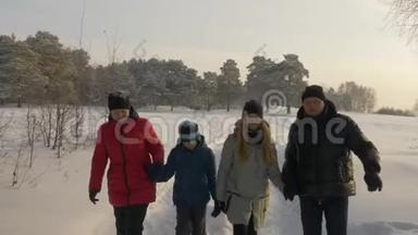 在阳光明媚的冬日，友好的家庭在雪林中散步。 冬季活动
