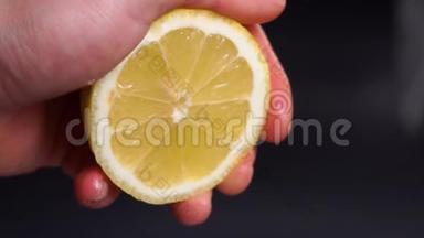 慢动作从柠檬中挤出果汁。 手捏新鲜柠檬。 柠檬汁水从纸浆和滴。