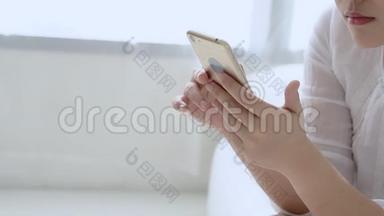 特写美丽的年轻亚洲女人坐着看着智能手机阅读社交网络与享受