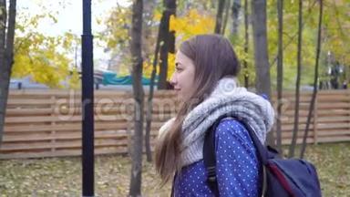 美丽的年轻女子戴着针织围巾，在秋天的公园散步。 视频运动