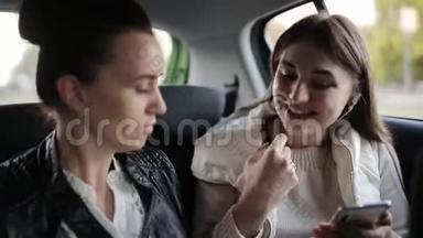 两个女孩坐出租车在后座说话和听音乐耳机。