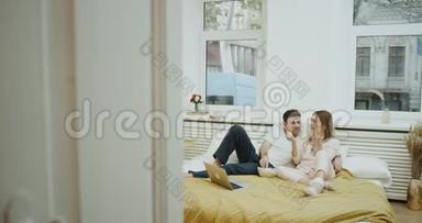 周末的时间，一对年轻夫妇穿着睡衣，整天躺在床上吃爆米花，在笔记本上看电影。 4k