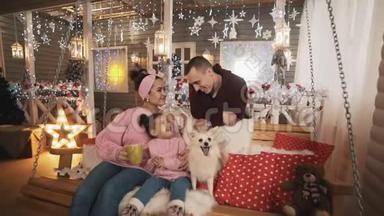 <strong>一家人</strong>带着<strong>女儿</strong>和白狗在门廊的圣诞长椅上玩得很开心