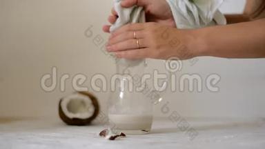 在家准备纯素椰奶的女人。 把牛奶倒入奶酪布中过滤。 替代牛奶