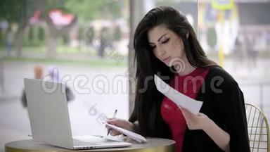 漂亮的年轻女孩穿着西装找工作，填写表格或简历，看着坐在咖啡馆里的笔记本电脑。 概念