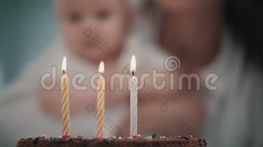 妈妈在婴儿生日蛋糕上吹了三支蜡烛。 宝宝生日派对理念