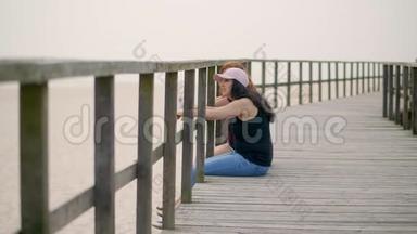 年轻女子坐在沙滩上的木墩上