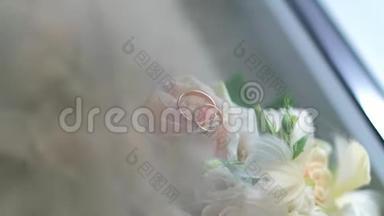 白色玫瑰上金色结婚戒指的特写。