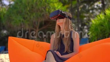 年轻<strong>女子坐在</strong>热带海滩的充气<strong>沙发上</strong>使用VR眼镜。 现代技术概念