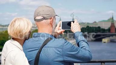 高层情侣站在观景台上，用手机拍摄城市的旅游照片