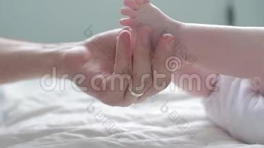 父亲抚摸并数着他的新生儿`小脚趾。 关上门。 父母抱着新生儿的脚。 快乐的父母。