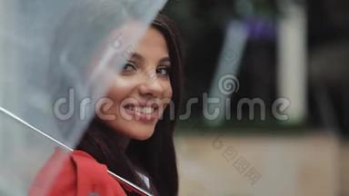 在城市的伞下微笑的女人看着镜头的肖像。 春季或秋季