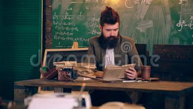 一位留胡子的老师在一个绿色黑板的背景下在学校教室里<strong>总结</strong>和阅读一本书。 学习概念