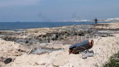 岩石海滩上的金属<strong>垃圾</strong>，背景是渔夫和船。 <strong>海洋</strong>污染。