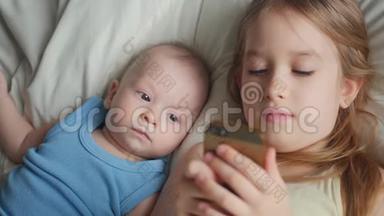两个孩子在床上一起使用和<strong>玩手机</strong>。 孩子们在卧室的床上一起用电话